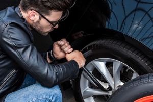 ragazzo aggiusta ruota auto